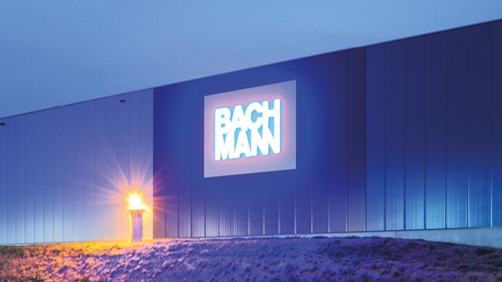 Das Bachmann Logo auf einer Lagerhalle von Bachmann in der Dämmerung
